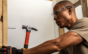 Man using a Crescent general purpose hammer to hammer a nail into framing