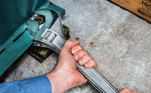 Man using a large Crescent adjustable wrench to loosen a hex fastener