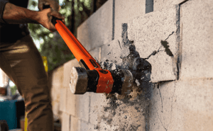 Man using a Crescent HEADLOCK sledgehammer to break a cinder block wall