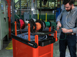 Male electrician using the RAILWORKS industrial utility cart outfitted with the mesh single door security panel, and wire spool holders in an industrial MRO setting