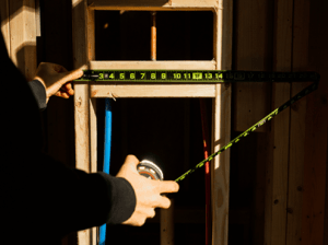 Man using a Crescent NITE EYE tape measure to measure framing in a new home build
