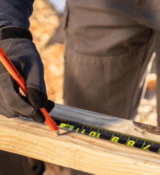 Male general contractor using Crescent NITE EYE tape measure to measure a piece of lumber
