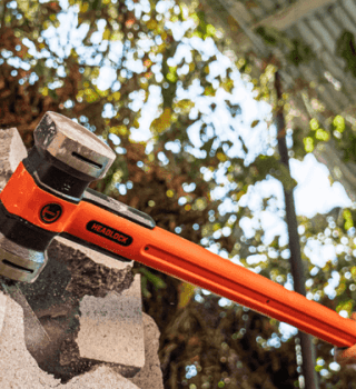 Man using a Crescent HEADLOCK sledgehammer to break a cinder block wall