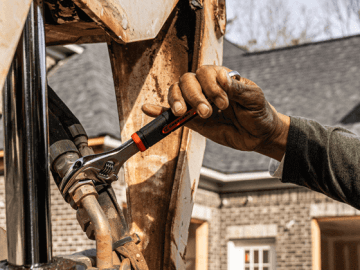 Male construction working using a Crescent adjustable wrench to fix a front loader