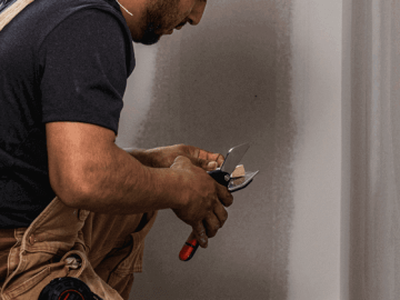 Male contractor using the Crescent Wiss miter snips to cut finishing to the correct size and angle